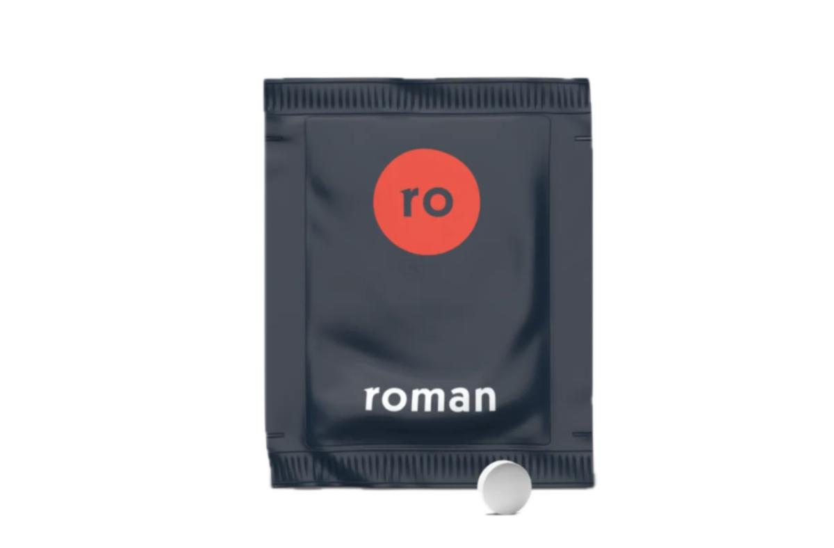 A grey and red individual use packet of a Roman dietary supplement with a white tablet in front of the packet.
